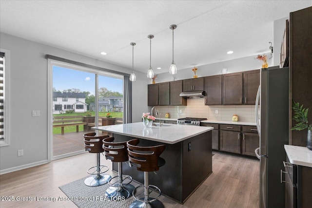 5651 Copper Creek Dr, Haslett, MI 48840 - kitchen featuring freestanding refrigerator, under cabinet range hood, a sink, light wood-type flooring, and recessed lighting