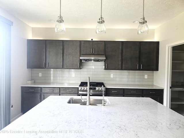 5651 Copper Creek Dr, Haslett, MI 48840 - kitchen featuring pendant lighting, under cabinet range hood, decorative backsplash, a textured ceiling, and light stone countertops