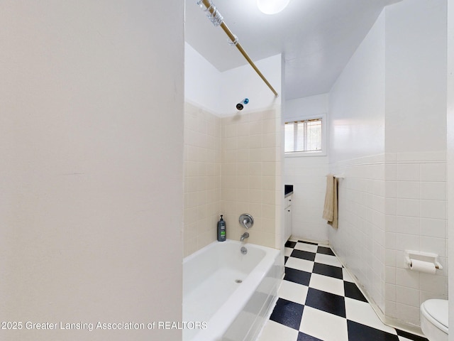 5120 Wardcliff Dr, East Lansing, MI 48823 - full bathroom with tile patterned floors, shower / bathtub combination, tile walls, toilet, and a wainscoted wall