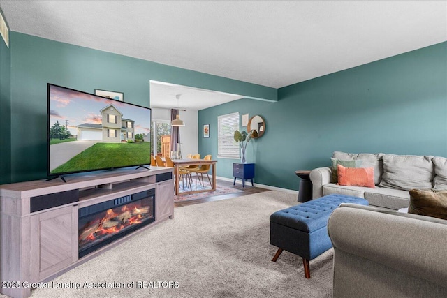 carpeted living area with a glass covered fireplace and baseboards