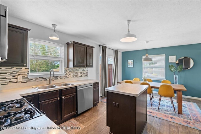 kitchen with stainless steel dishwasher, a sink, backsplash, dark brown cabinetry, and a textured ceiling