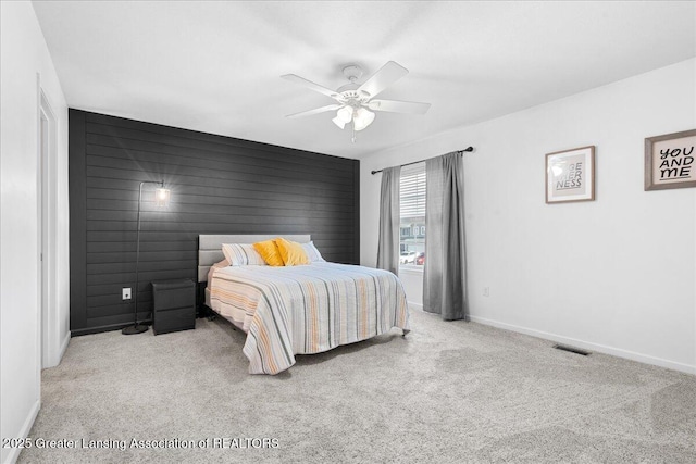 carpeted bedroom with baseboards, a ceiling fan, and an accent wall