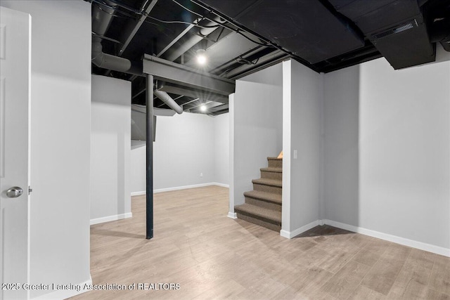 finished below grade area featuring wood finished floors, baseboards, and stairs
