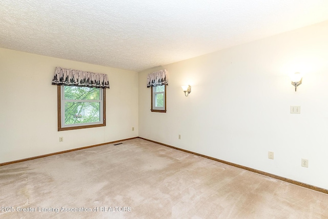 unfurnished room featuring light carpet, baseboards, and a textured ceiling