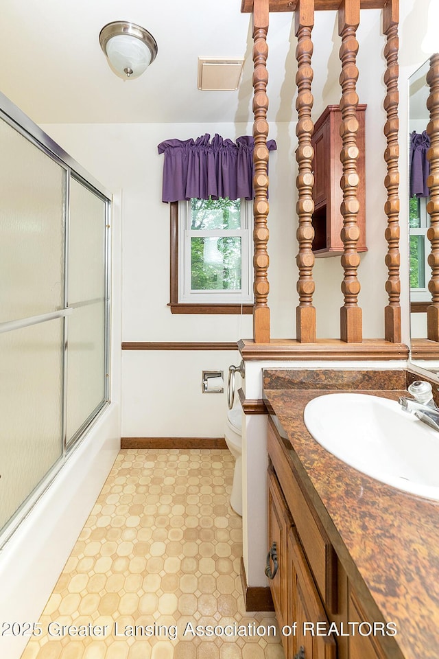 full bathroom with plenty of natural light, tile patterned floors, toilet, and bath / shower combo with glass door