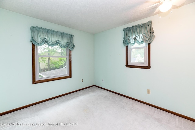 carpeted spare room featuring plenty of natural light, baseboards, a textured ceiling, and ceiling fan