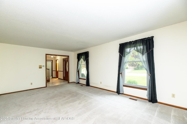 spare room featuring light carpet and baseboards