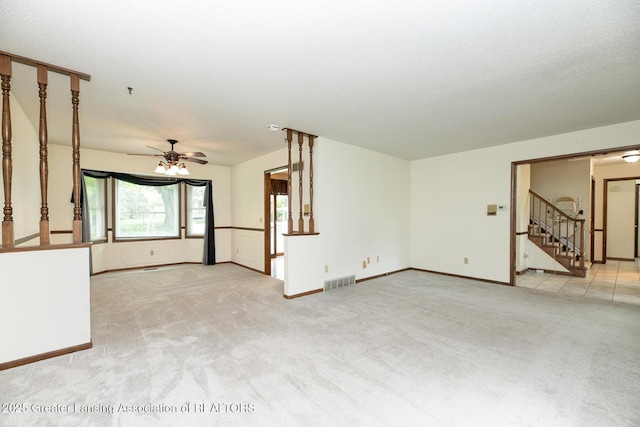 unfurnished living room featuring stairway, ceiling fan, light carpet, and baseboards