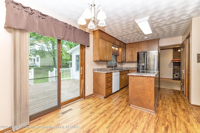 kitchen with stainless steel refrigerator with ice dispenser, white dishwasher, brown cabinets, a chandelier, and light wood finished floors