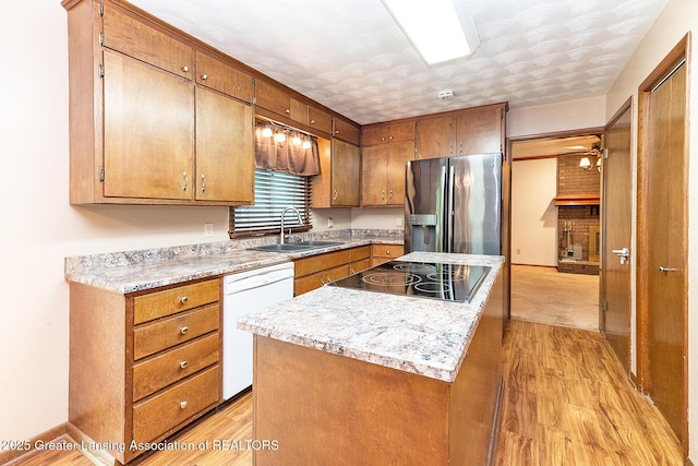 kitchen with stainless steel fridge, dishwasher, black electric stovetop, a sink, and a center island
