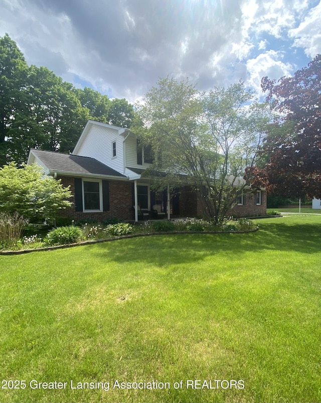 view of front facade featuring brick siding and a front yard
