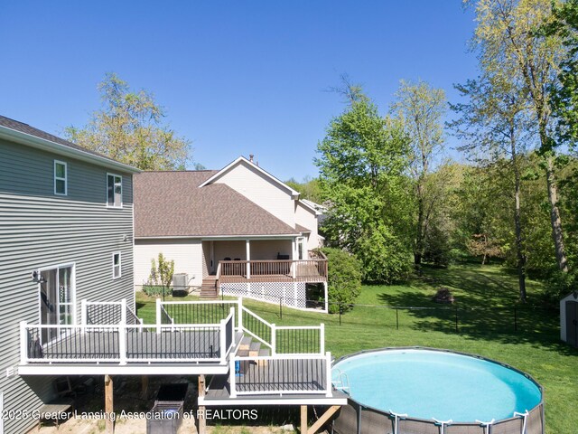 3793 Calypso Rd, Holt, MI 48842 - rear view of house featuring a wooden deck, an outdoor pool, and a shingled roof
