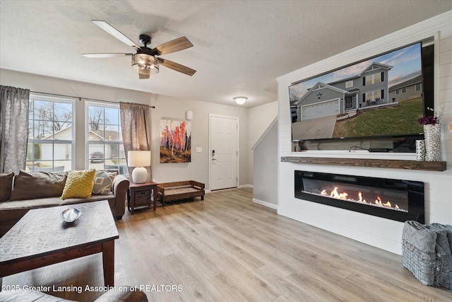 3793 Calypso Rd, Holt, MI 48842 - living area with wood finished floors, a ceiling fan, a glass covered fireplace, baseboards, and a textured ceiling