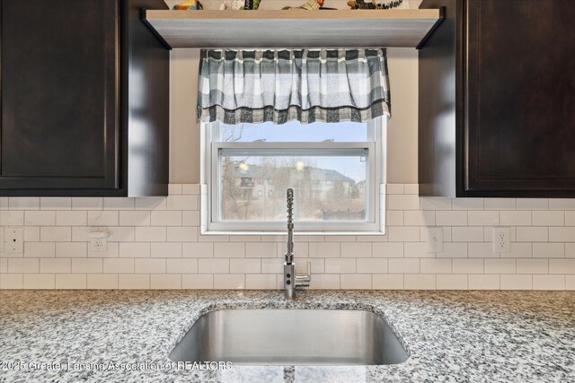 3793 Calypso Rd, Holt, MI 48842 - kitchen view of a sink, dark brown cabinets, backsplash, and light stone countertops