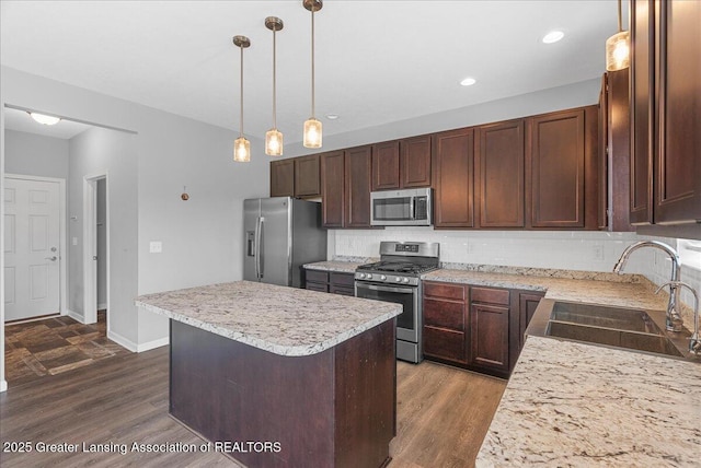 4535 Harper Rd, Holt, MI 48842 - kitchen with appliances with stainless steel finishes, a sink, light countertops, backsplash, and a center island