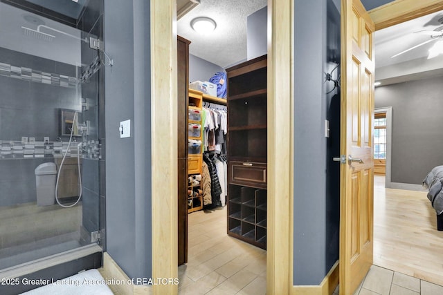 3650 Observatory Ln, Holt, MI 48842 - bathroom featuring a tile shower, a spacious closet, baseboards, tile patterned floors, and a textured ceiling