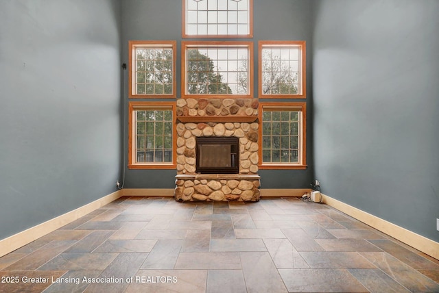 3650 Observatory Ln, Holt, MI 48842 - unfurnished living room featuring baseboards, a stone fireplace, stone finish floors, and a towering ceiling