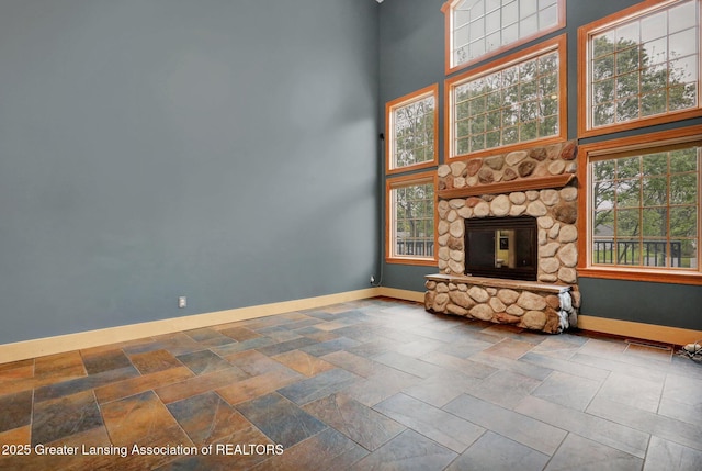 3650 Observatory Ln, Holt, MI 48842 - unfurnished living room featuring baseboards, a towering ceiling, a stone fireplace, healthy amount of natural light, and stone finish flooring