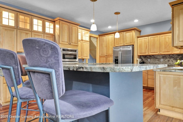 3650 Observatory Ln, Holt, MI 48842 - kitchen featuring appliances with stainless steel finishes, a breakfast bar, light wood-type flooring, glass insert cabinets, and backsplash