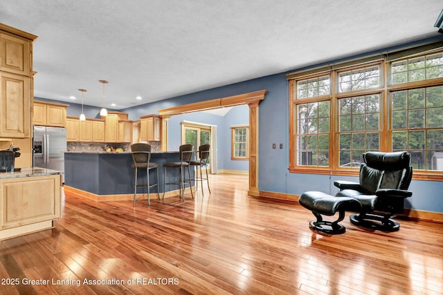 3650 Observatory Ln, Holt, MI 48842 - kitchen featuring stainless steel fridge with ice dispenser, light wood-style floors, backsplash, light brown cabinetry, and a kitchen breakfast bar