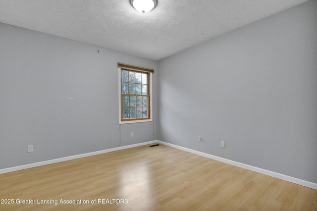 3650 Observatory Ln, Holt, MI 48842 - empty room with light wood finished floors, a textured ceiling, and baseboards
