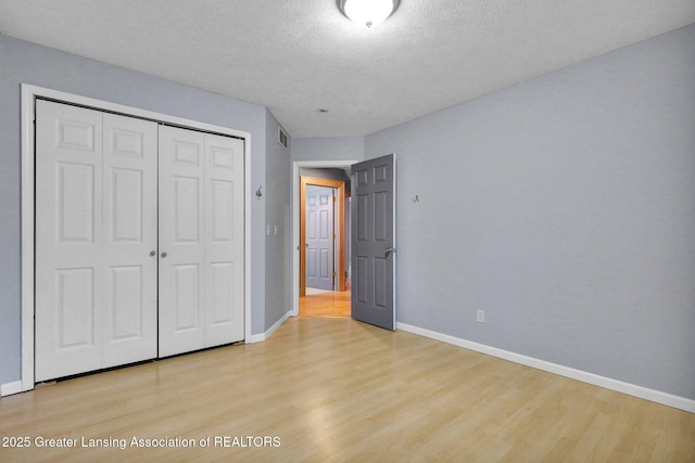 3650 Observatory Ln, Holt, MI 48842 - unfurnished bedroom featuring light wood finished floors, a closet, baseboards, and a textured ceiling