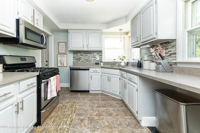 2531 Dillingham Ave, Lansing, MI 48906 - kitchen with stainless steel appliances, decorative backsplash, light stone finish floors, white cabinets, and a sink