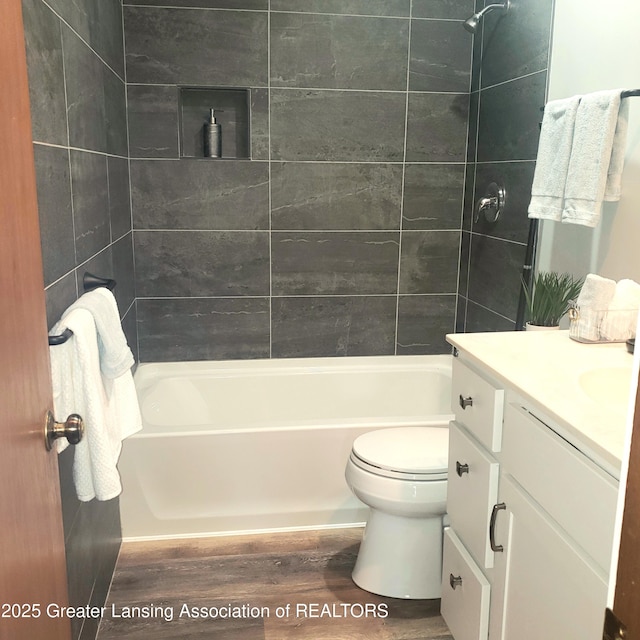 bathroom featuring wood finished floors, washtub / shower combination, toilet, and vanity