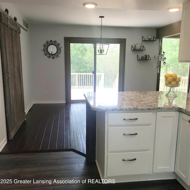 kitchen with white cabinetry, a barn door, healthy amount of natural light, and recessed lighting
