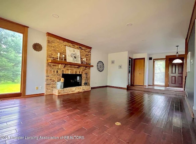 unfurnished living room with dark wood finished floors, baseboards, and a fireplace