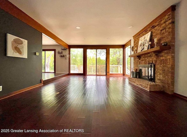unfurnished living room with dark wood-style floors, baseboards, and a brick fireplace