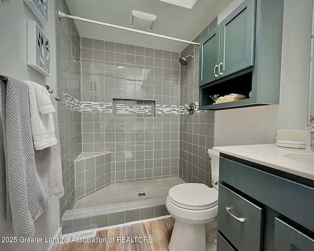 full bathroom with tiled shower, vanity, and toilet