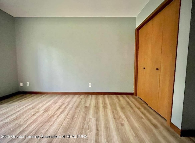 unfurnished bedroom with light wood-style flooring, a closet, and baseboards