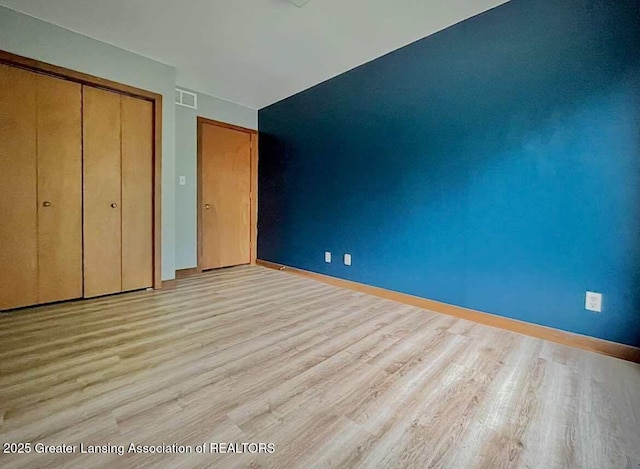 unfurnished bedroom with wood finished floors, a closet, and baseboards
