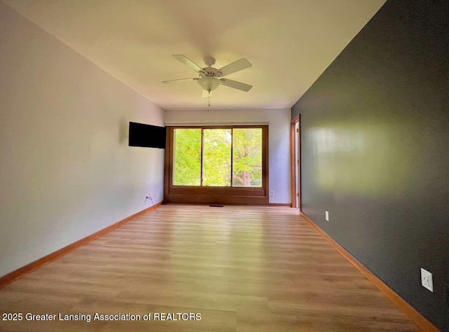 unfurnished room featuring light wood finished floors, ceiling fan, and baseboards