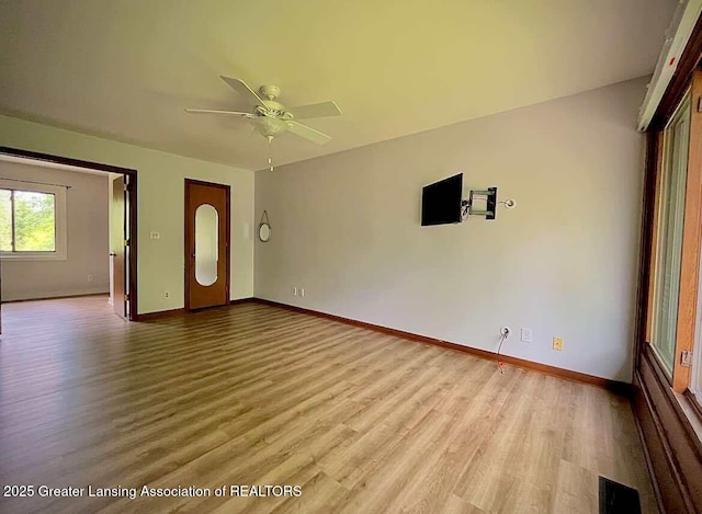empty room featuring wood finished floors, baseboards, and ceiling fan