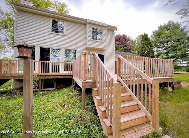 rear view of property featuring stairs, a wooden deck, and a chimney