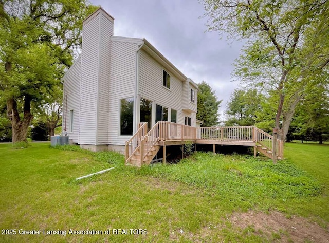 rear view of house with a deck, a chimney, a yard, and stairway