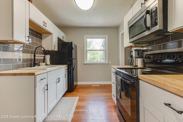 316 Union St, Grand Ledge, MI 48837 - kitchen featuring black appliances, butcher block counters, a sink, and tasteful backsplash