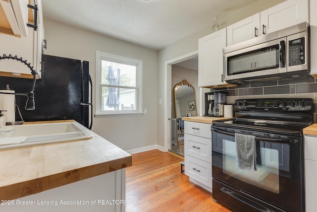 316 Union St, Grand Ledge, MI 48837 - kitchen featuring black appliances, butcher block counters, white cabinets, a sink, and light wood finished floors