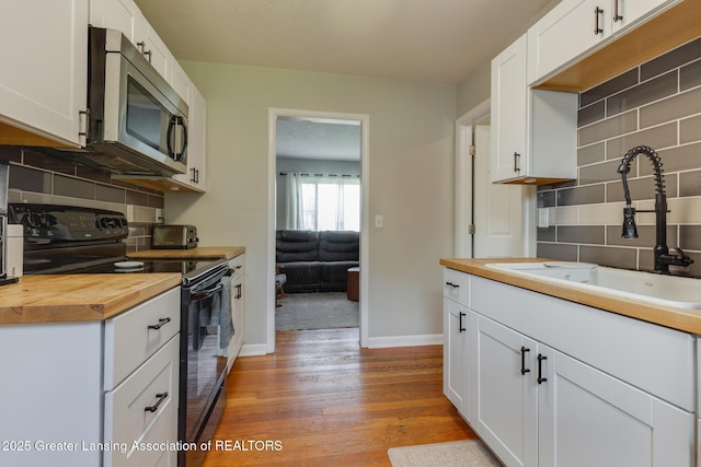 316 Union St, Grand Ledge, MI 48837 - kitchen with electric range, stainless steel microwave, wood counters, a sink, and backsplash