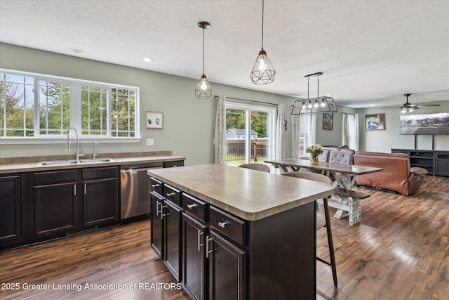 703 Josie Ln, Laingsburg, MI 48848 - kitchen with a sink, a kitchen bar, dark wood-style floors, stainless steel dishwasher, and pendant lighting