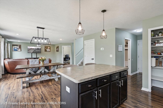 703 Josie Ln, Laingsburg, MI 48848 - kitchen with dark wood-type flooring, open floor plan, dark cabinets, a center island, and pendant lighting
