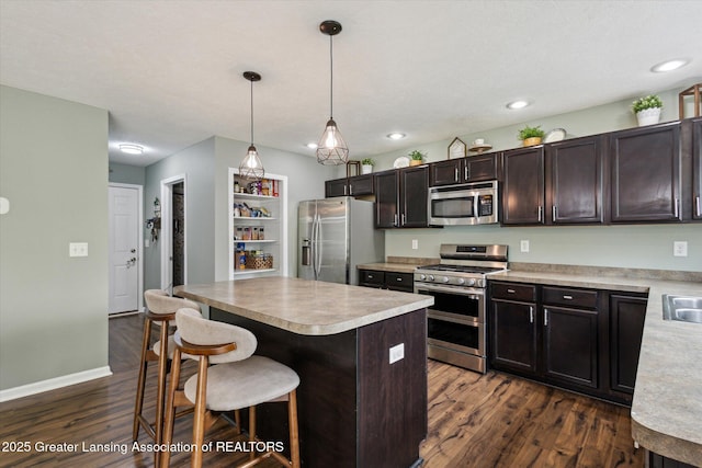 703 Josie Ln, Laingsburg, MI 48848 - kitchen with stainless steel appliances, dark wood-style flooring, a kitchen bar, light countertops, and a kitchen island