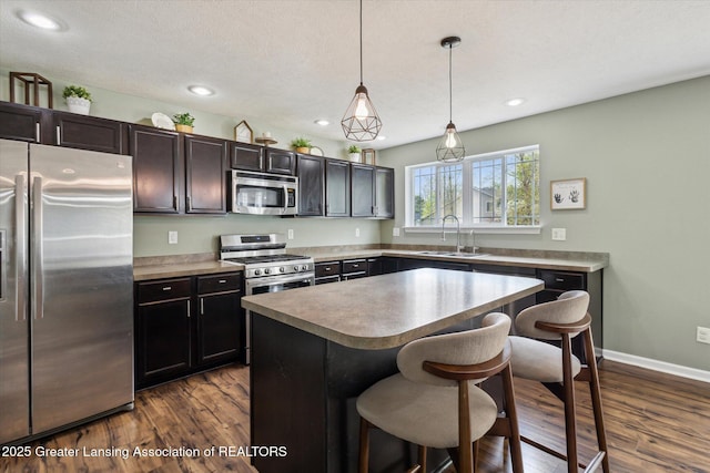 703 Josie Ln, Laingsburg, MI 48848 - kitchen with appliances with stainless steel finishes, a sink, a breakfast bar area, dark wood-style floors, and recessed lighting