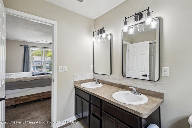 703 Josie Ln, Laingsburg, MI 48848 - bathroom featuring ensuite bath, double vanity, decorative backsplash, and baseboards