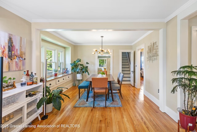 1038 Morgan St, Lansing, MI 48912 - dining room featuring light wood-style flooring, a chandelier, crown molding, baseboards, and stairs