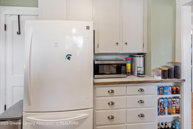 1038 Morgan St, Lansing, MI 48912 - kitchen with freestanding refrigerator, stainless steel microwave, white cabinetry, and light countertops