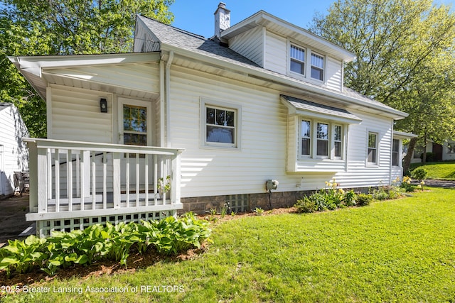 1038 Morgan St, Lansing, MI 48912 - view of front facade with a front yard, a chimney, roof with shingles, and a wooden deck