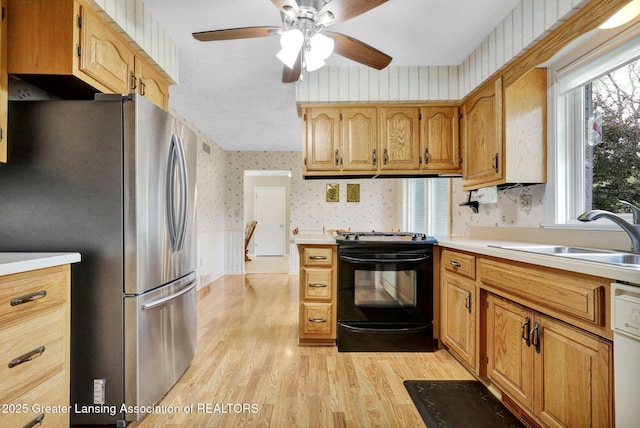 10079 Woodland Acres Dr, Grand Ledge, MI 48837 - kitchen featuring wallpapered walls, black range, freestanding refrigerator, a sink, and light wood-style flooring